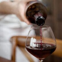 Waiter pours red wine into a wine glass